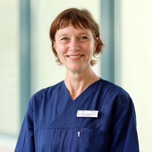 Eine Frau mit kurzen Haaren und einem blauen Kittel