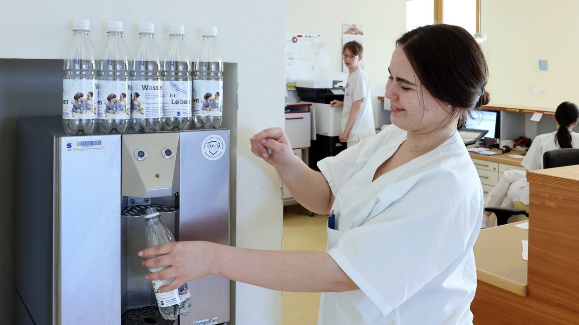Foto einer Pflegekraft, die einen Wasserspender in den Sana Kliniken Niederlausitz bedient.