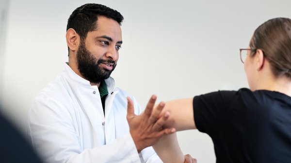 Mohamed Mahde bei der Untersuchung des Ellbogens und Schultergelenks einer Patientin.