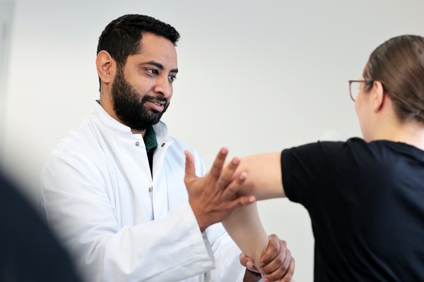 Mohamed Mahde bei der Untersuchung des Ellbogens und Schultergelenks einer Patientin.