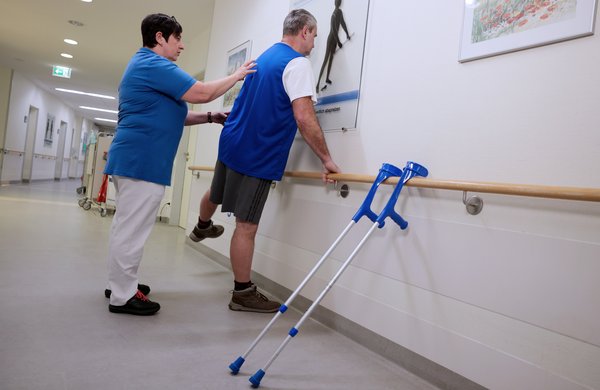 Eine Physiotherapeutin unterstützt einen Patienten bei Übungen.